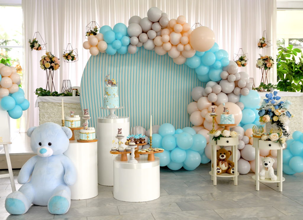 Elegant baby shower setup with floral arrangements, balloon decorations, styled dessert table, and soft neutral color palette for a memorable celebration.